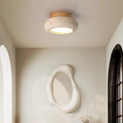 Plafonnier travertin bois clair dans une entrée avec miroir organique et arche