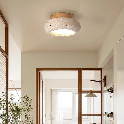 Plafonnier travertin et bois clair éclairant une pièce lumineuse au style japandi