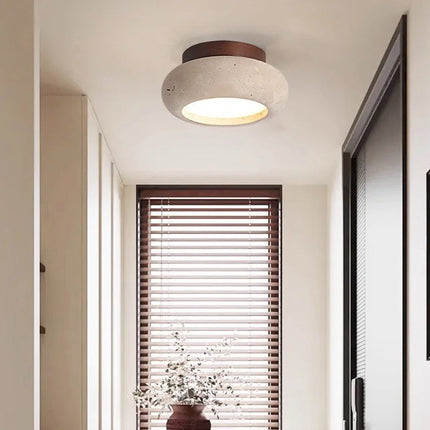 Plafonnier galet travertin bois foncé éclairant un couloir décoré de fleurs séchées