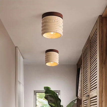 Dos plafones de travertino natural que iluminan un pasillo de puertas de madera clara