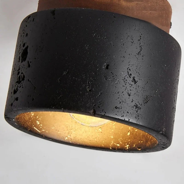 Détail du plafonnier travertin noir et bois allumé vu de trois quarts