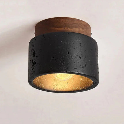 Plafonnier travertin noir et bois allumé diffusant une lumière chaude vers le bas
