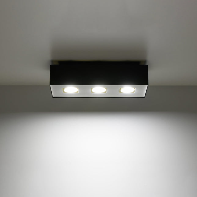 Plafonnier Triple Raffiné noir projetant un faisceau de lumière vers le bas