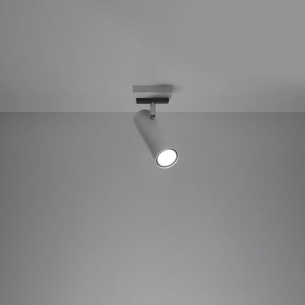 Plafonnier tube ajustable blanc allumé, faisceau dirigé sur un mur gris