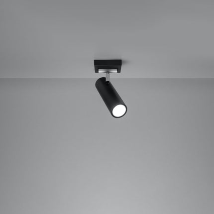 Plafonnier tube ajustable noir allumé, faisceau dirigé sur un mur gris