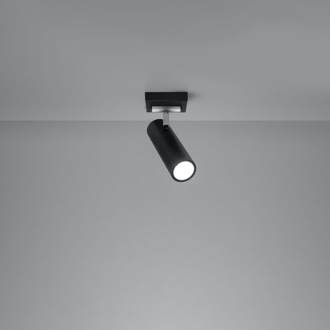 Plafonnier tube ajustable noir allumé, faisceau dirigé sur un mur gris
