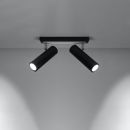 Plafonnier tube ajustable noir à deux spots allumé, faisceaux dirigés sur un mur gris