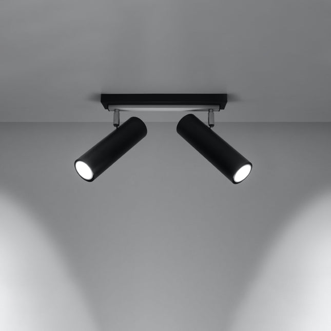 Plafonnier tube ajustable noir à deux spots allumé, faisceaux dirigés sur un mur gris