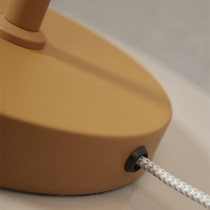 Gros plan sur le petit bouton intégré au tube de la lampe Porto moutarde