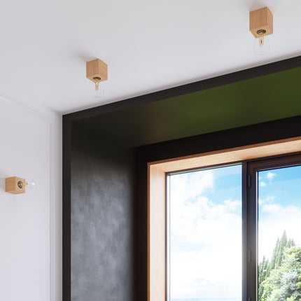 Cubes en bois naturel disposés près d'une fenêtre, ampoules filament apparentes, intérieur lumineux.