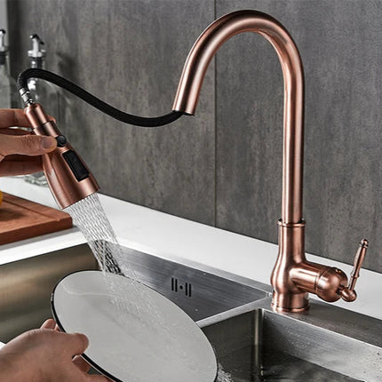 Robinet de cuisine rouge cuivré, douchette extractible en main rinçant une assiette