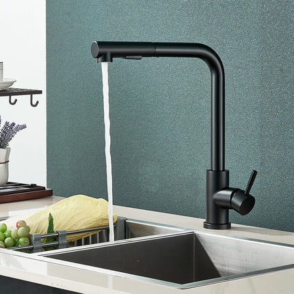 Robinet de cuisine inox noir mat installé sur un évier, mur vert et légumes