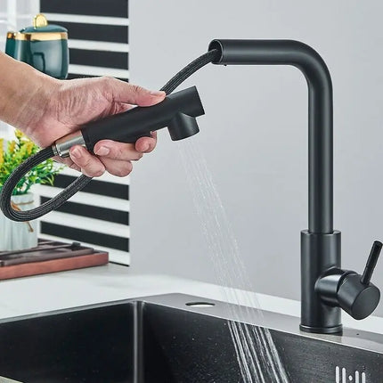 Robinet de cuisine inox noir mat, douchette en main délivrant un jet pluie dans l'évier