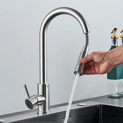 Mano que tira de la ducha retráctil de un grifo mezclador de cocina de acero cepillado