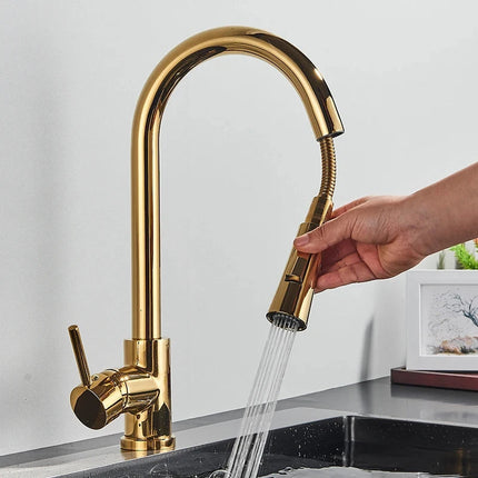 Mano que tira de la ducha retráctil de un grifo mezclador de cocina dorado brillante