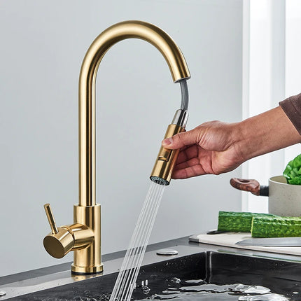Mano que tira de la ducha retráctil de un grifo mezclador de cocina dorado cepillado
