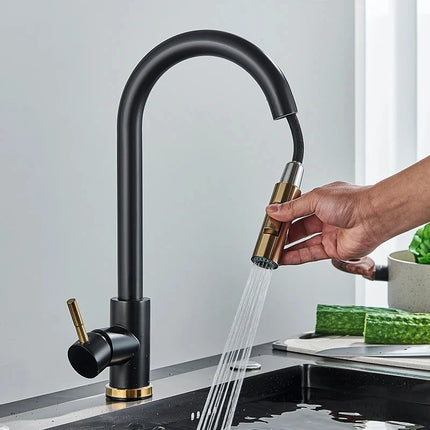 Mano que tira de la ducha retráctil de un grifo mezclador de cocina negro y dorado