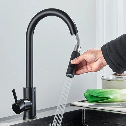 Mano que tira de la ducha retráctil de un grifo mezclador de cocina negro mate
