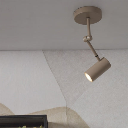 Spot plafonnier Montreux en fer sable fixé au plafond, bras articulé orienté vers le mur