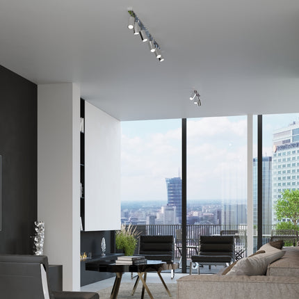 Ambiance appartement lumineux avec spots chromés au plafond près d'une grande baie vitrée