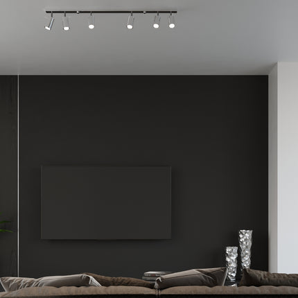 Ambiance salon contemporain sombre éclairé par une rampe de spots chromés au plafond