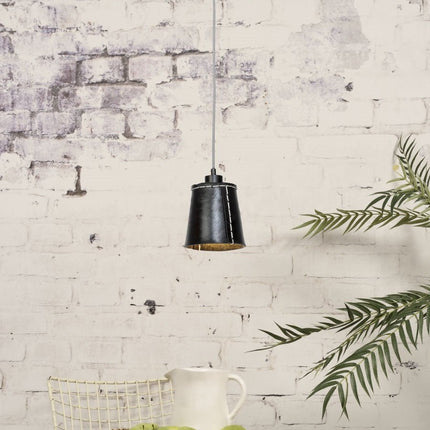 Pendant light Amazon in black recycled rubber hanging in front of a wall of brick whitewashed