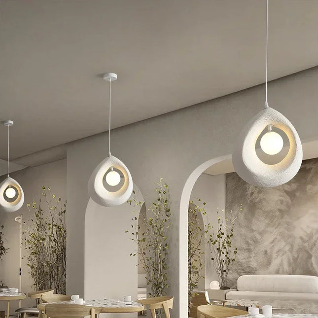 Suspensions anneau sablé blanc alignées au plafond d'un espace lumineux avec plantes et mobilier en bois clair