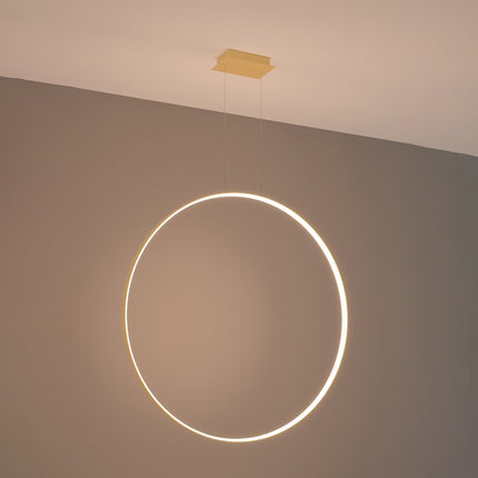 Grande suspension anneau doré Anneau Solis allumée, halo lumineux continu sur mur gris