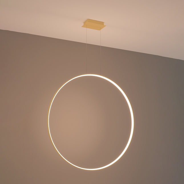 Grande suspension anneau doré Anneau Solis allumée, halo lumineux continu sur mur gris