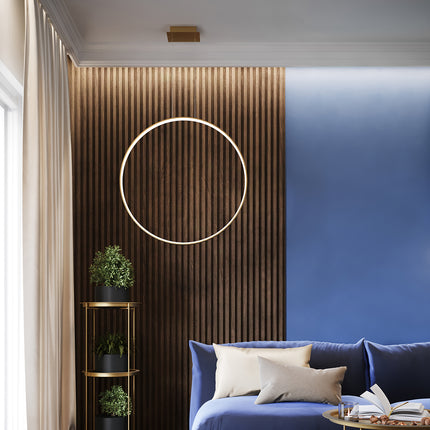 Suspension anneau doré Anneau Solis au-dessus d'une banquette bleue, mur en lattes de bois