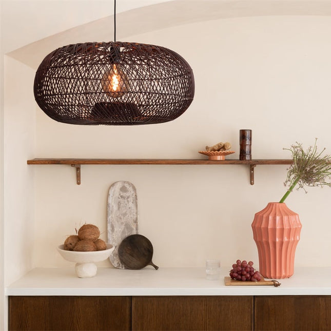 Suspension Arizona en bambou tressé bordeaux allumée au-dessus d'une étagère en bois avec vase rose