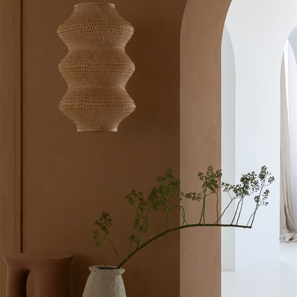 Suspension Barbados en bambou tressé naturel au-dessus d'un plan de travail, dans une pièce aux tons terracotta.