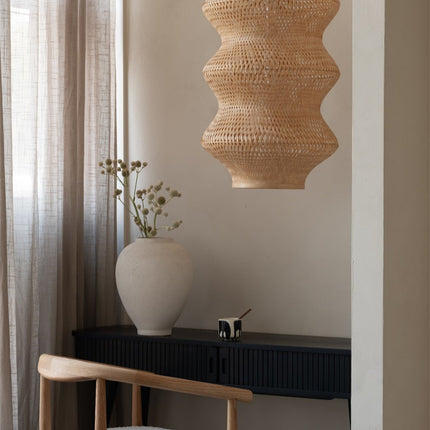 Suspension Barbados en bambou naturel accrochée près d'un fauteuil en bois clair, ambiance chaleureuse et épurée.