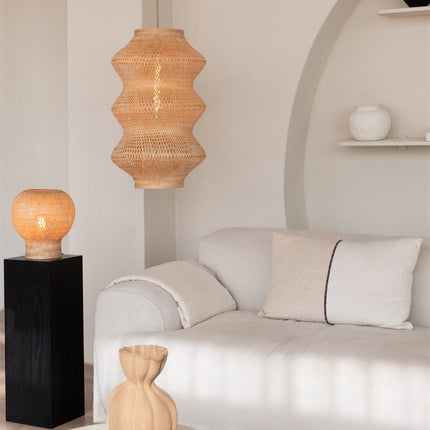 Suspension Barbados en bambou naturel au-dessus d'un canapé, avec une lampe à poser assortie sur un socle noir.