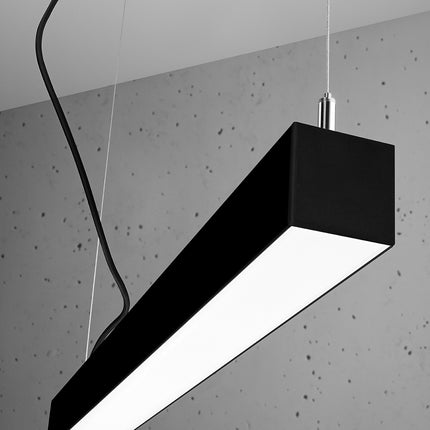Suspension barre moderne LED noire 118 cm allumée vue d'angle, câbles apparents sur béton