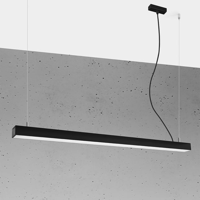 Suspension barre moderne LED noire 118 cm allumée, profil aluminium sur un mur de béton