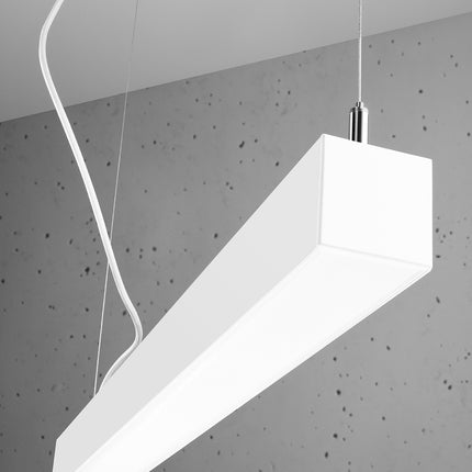 Suspension barre moderne LED blanche 90 cm allumée vue d'angle, câbles apparents sur béton