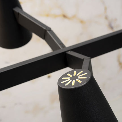 Suspension Biarritz fer noir éclairant une table en bois avec des chaises noires