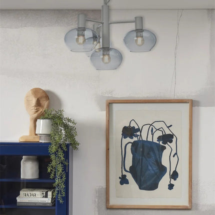 Suspension Bologna 4 bras verre gris dégradé dans un salon japandi avec cadre bleu et bibliotheque