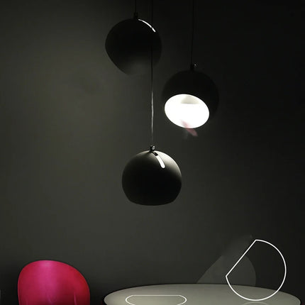 Suspensions boule en métal noir dans une ambiance tamisée, halo lumineux au-dessus d'une table