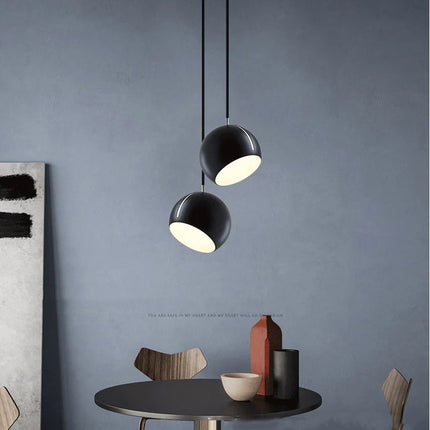 Deux suspensions boule en métal noir au-dessus d'une table à manger dans un intérieur contemporain