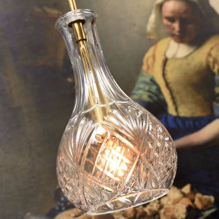 Gros plan sur les motifs taillés du verre de la suspension Brussels, ampoule allumée