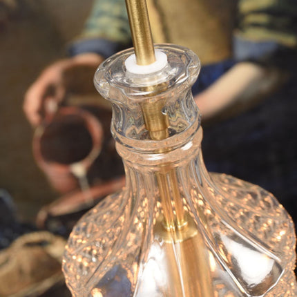 Gros plan sur les motifs taillés du verre de la suspension Brussels cylindrique, ampoule allumée