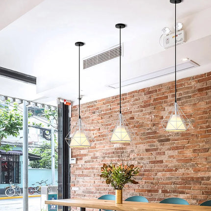 Suspensions cage diamant blanches devant un mur de briques, ambiance loft