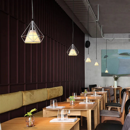 Suspensions cage diamant noires échelonnées dans un restaurant au mur bordeaux