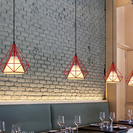 Suspensions cage diamant rouges devant un mur de briques peint dans un restaurant
