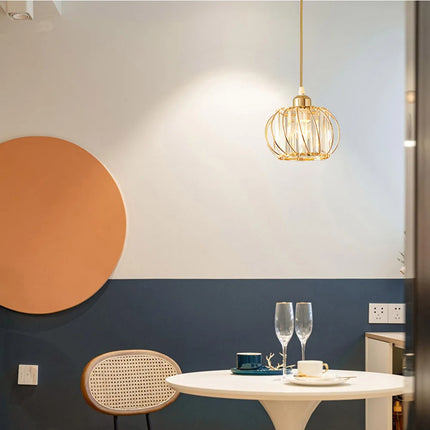 Suspension cage en métal doré et cristal au-dessus d'un coin repas bicolore