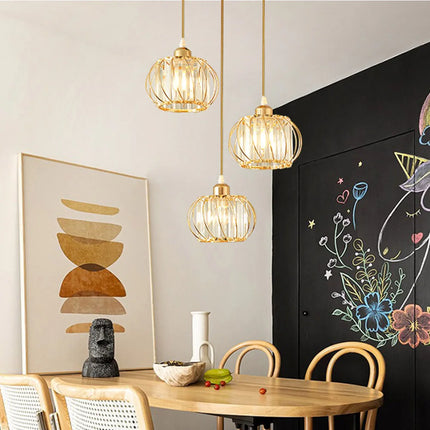 Trois suspensions cage en métal doré et cristal dans une salle à manger décorée