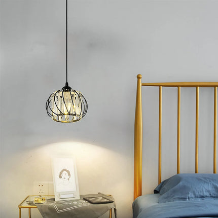 Suspension cage en métal noir et cristal au-dessus d'un chevet dans une chambre