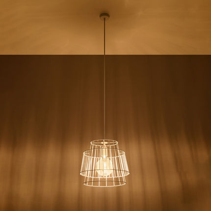 Suspension cage blanche allumée diffusant une lumière chaude et un jeu d'ombres graphiques sur le plafond.